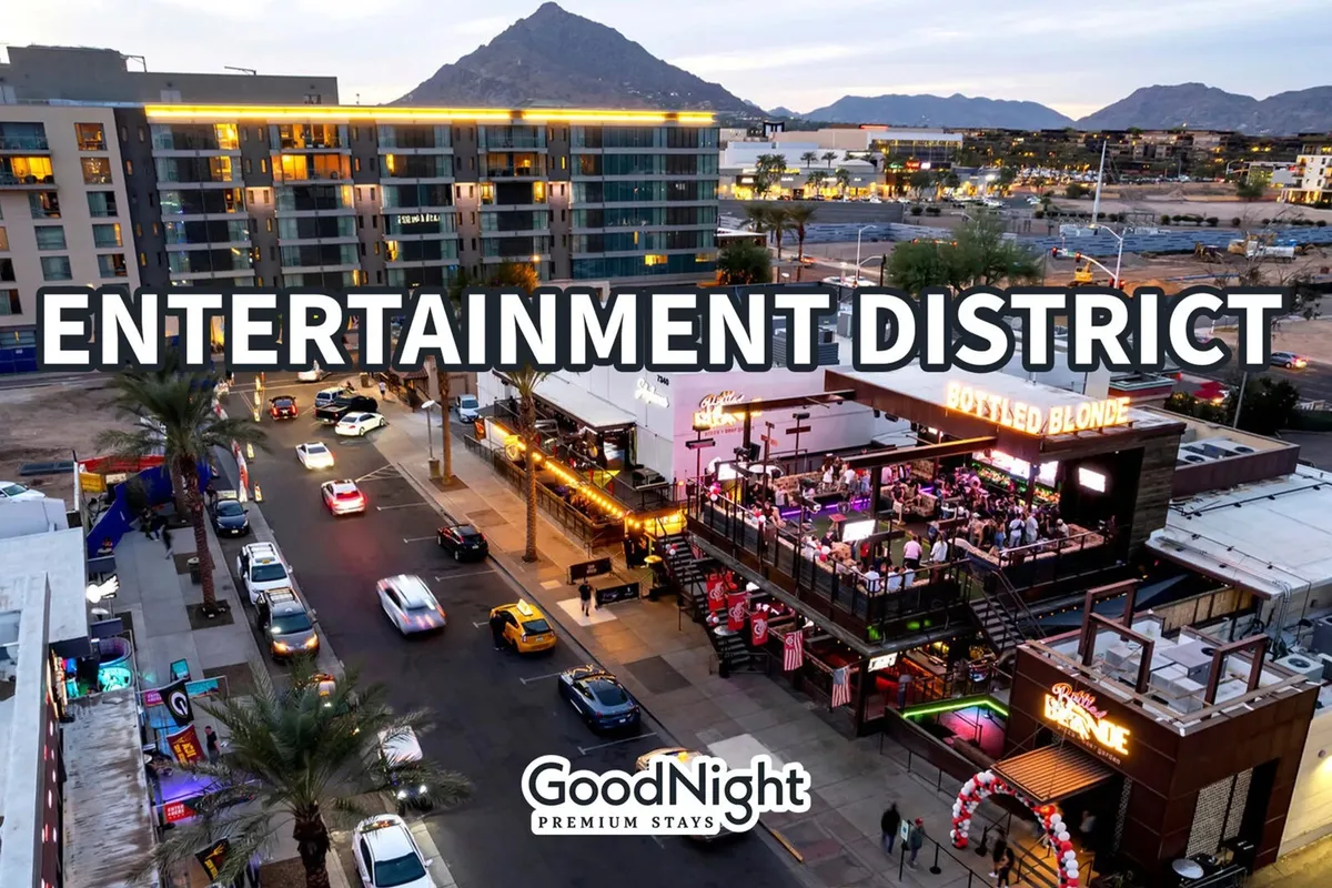 A lively street view of the Entertainment District, showing prominent signage, a bustling venue (Bottled Blonde), busy traffic, and mountains in the distance. The energetic scene reflects vibrant nightlife and local attractions.