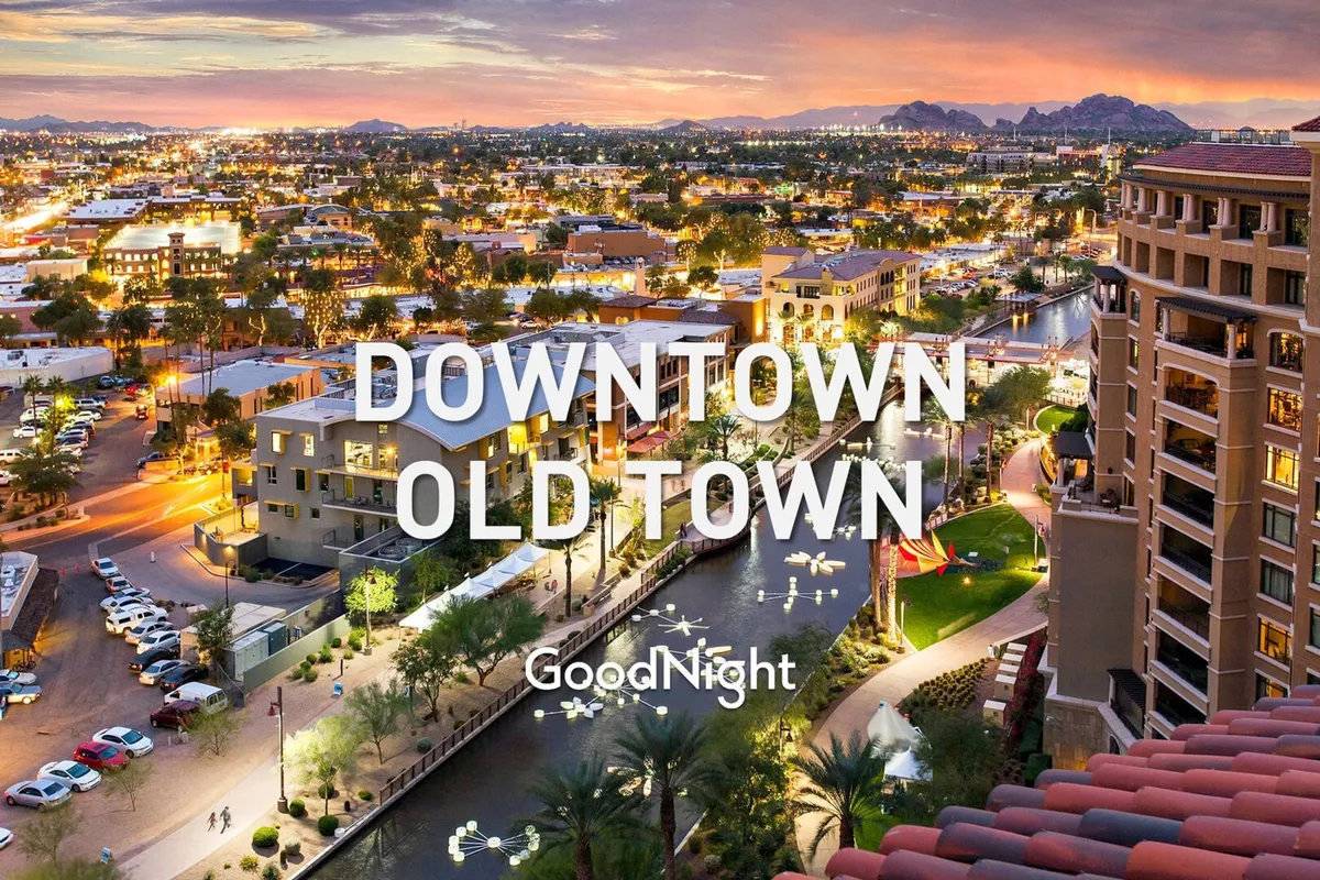 A scenic nighttime view of illuminated Old Town buildings alongside the canal, with mountains in the background. The setting is vibrant and inviting, hinting at bustling evening activities like dining, shopping, and enjoying the lively local atmosphere.