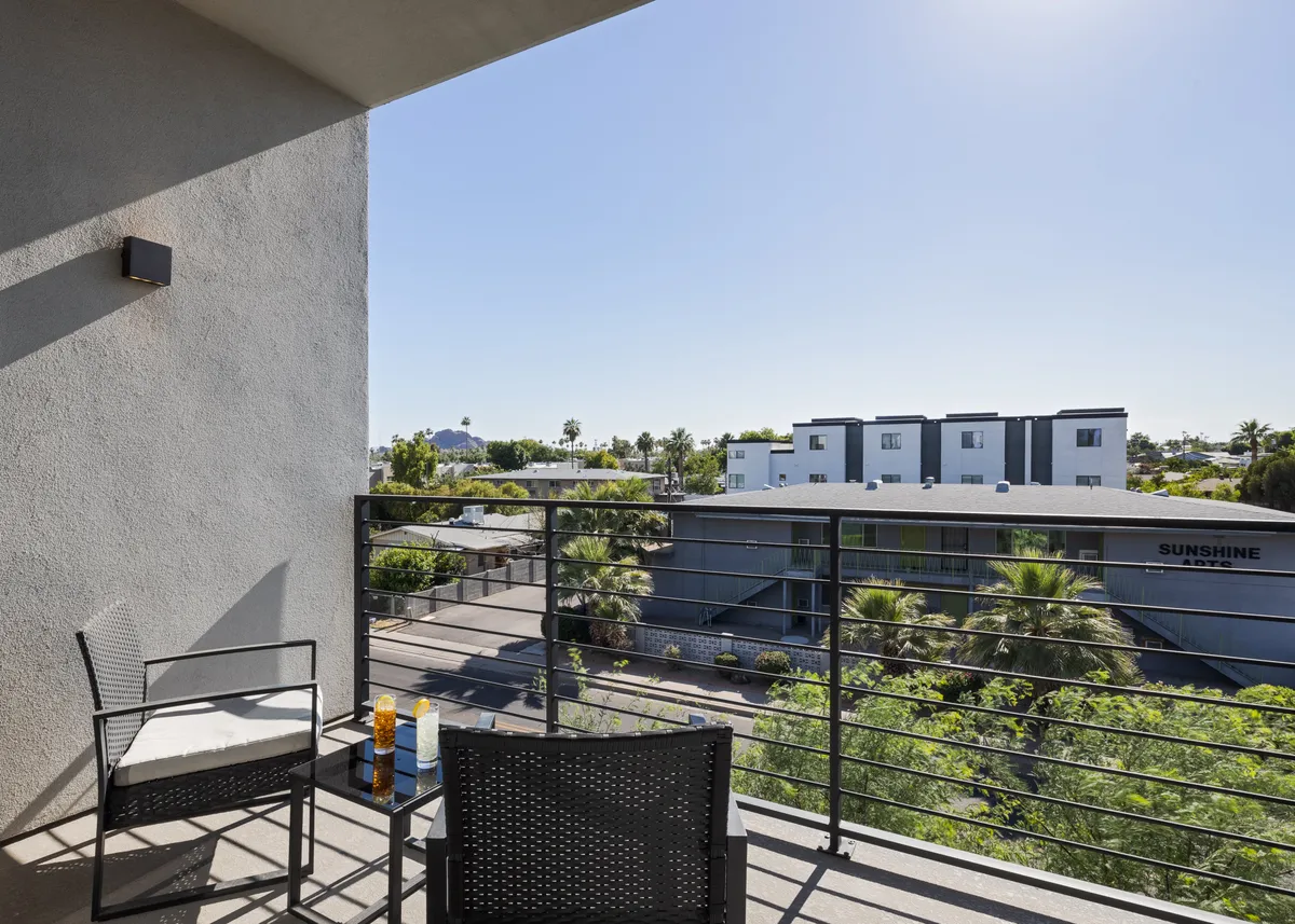 A tranquil private balcony with two chairs overlooking palm trees, perfect for relaxing with morning coffee or evening drinks after a day or night of adventure in Old Town.